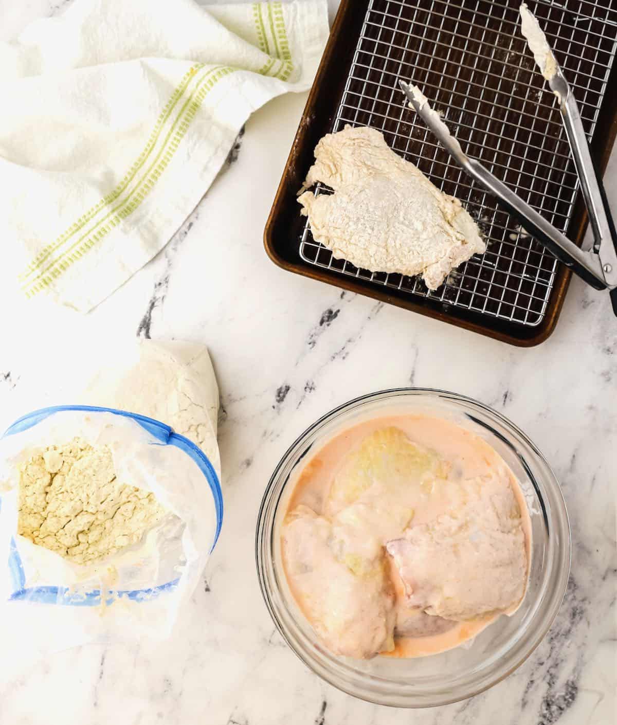 Chicken marinated in buttermilk being dredged in flour.