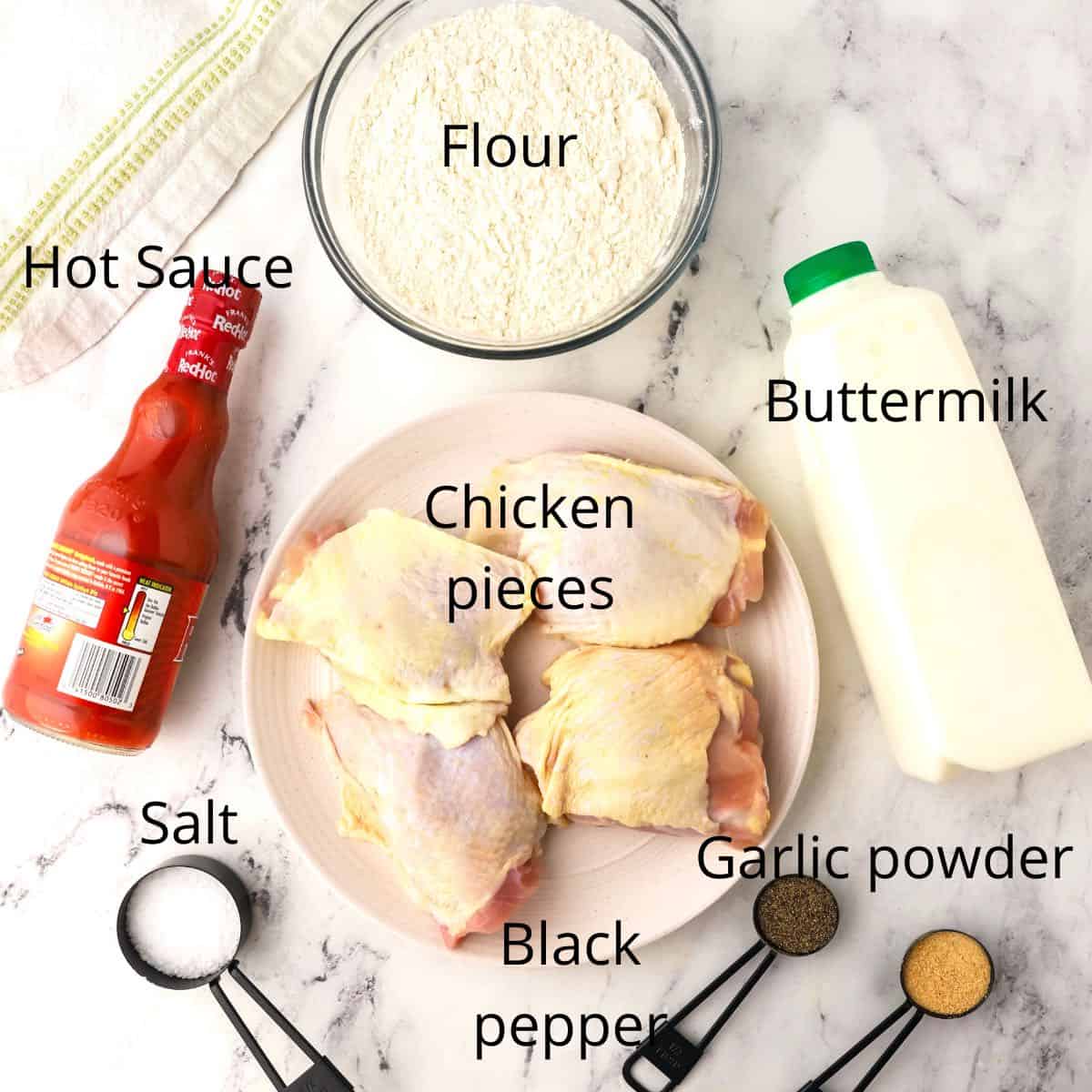 Ingredients for fried chicken including chicken thighs, buttermilk and flour.