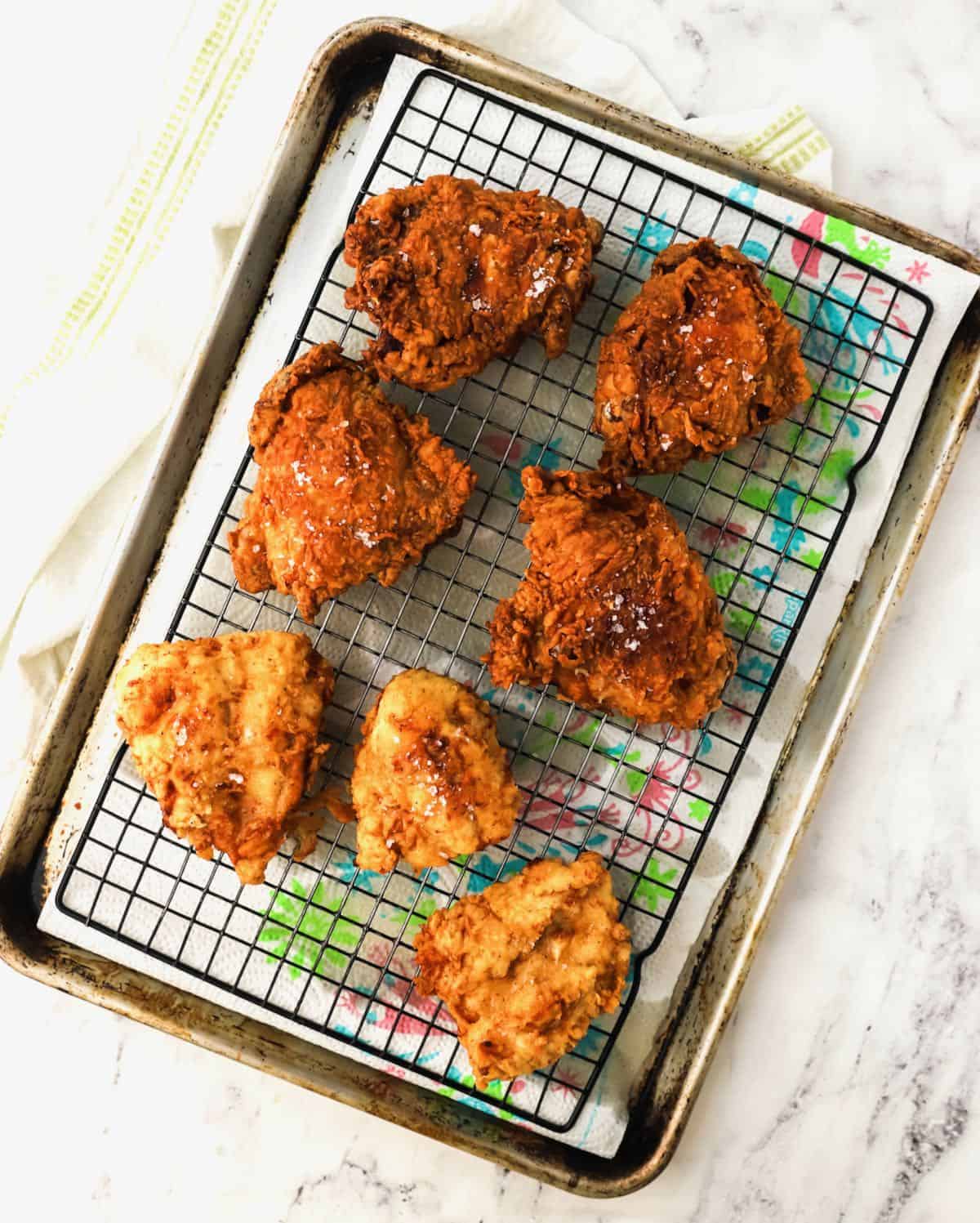 Fried chicken draining on a wire rack. 