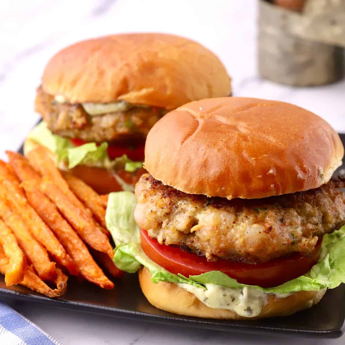 Two shrimp burgers with sweet potato fries.