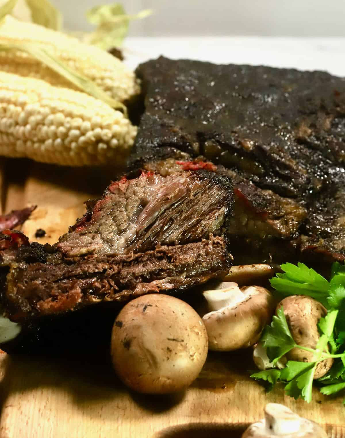 Smoked Beef Short Ribs on a cutting board with corn.