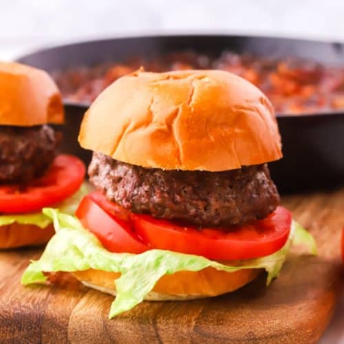 A burger with lettuce and tomato on a cutting board.