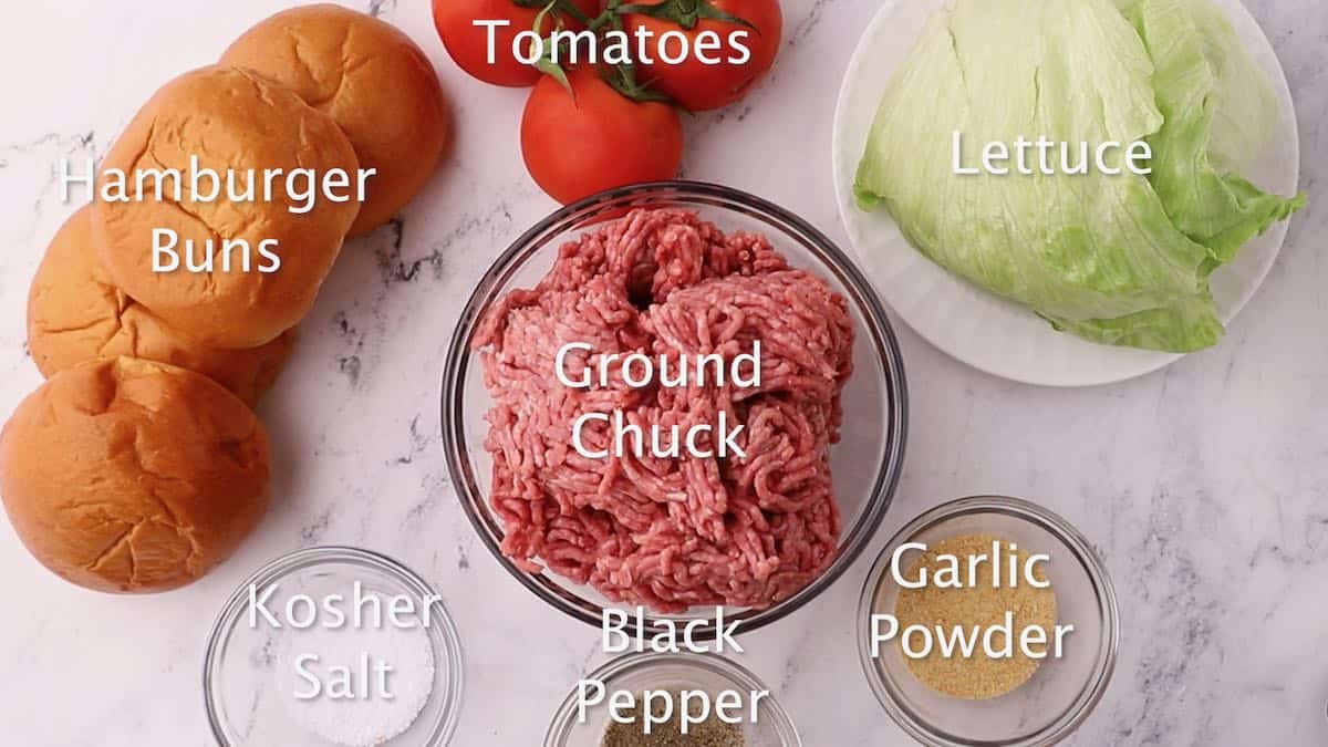 A bowl of ground chuck, lettuce, tomatoes, and seasonings. 