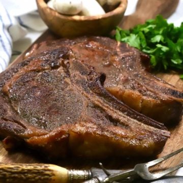 Two smoked ribeye steaks on a cutting board.