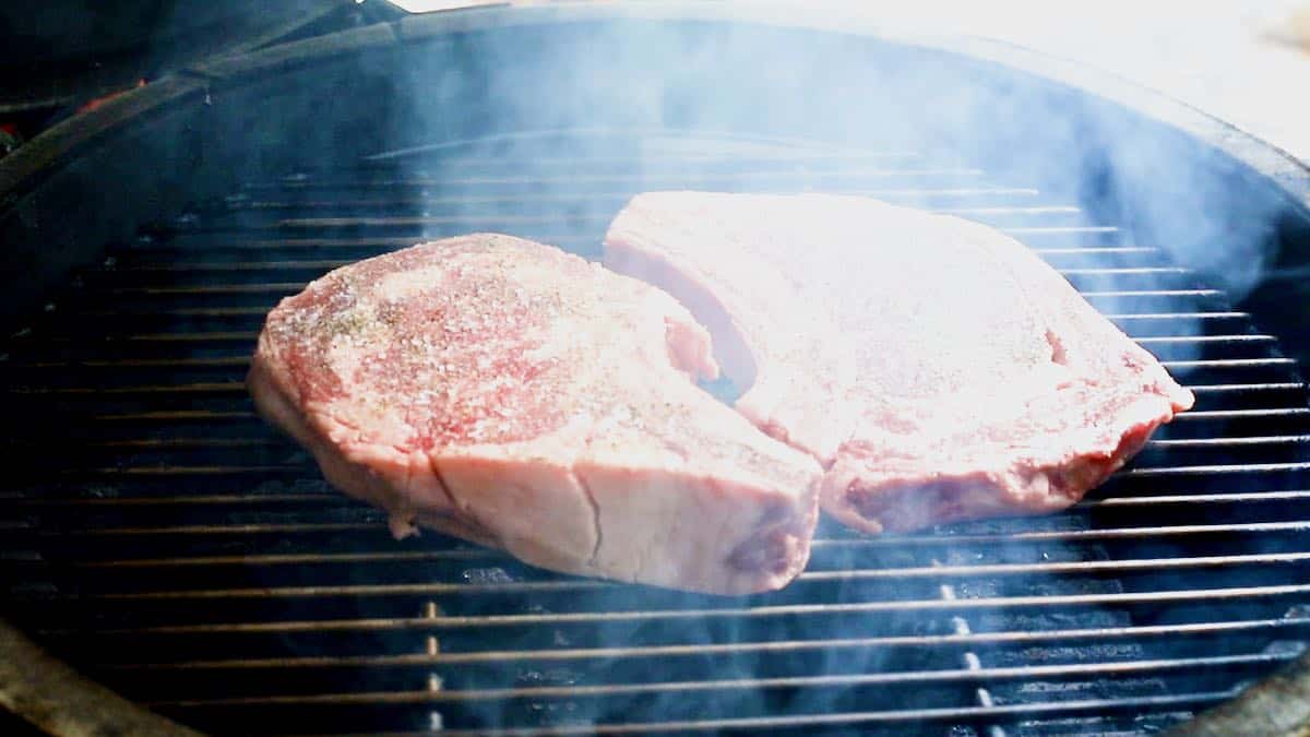Steaks smoking on a grill. 