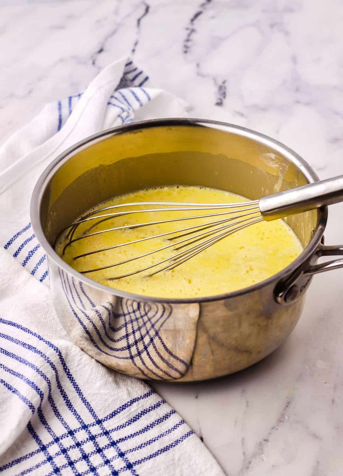 Vanilla custard in a saucepan with a whisk. 