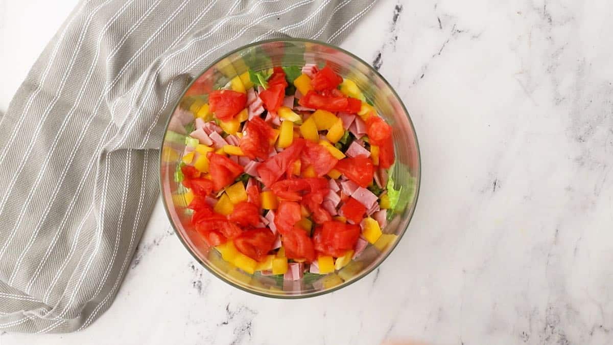 A layer of chopped tomatoes in a trifle dish. 