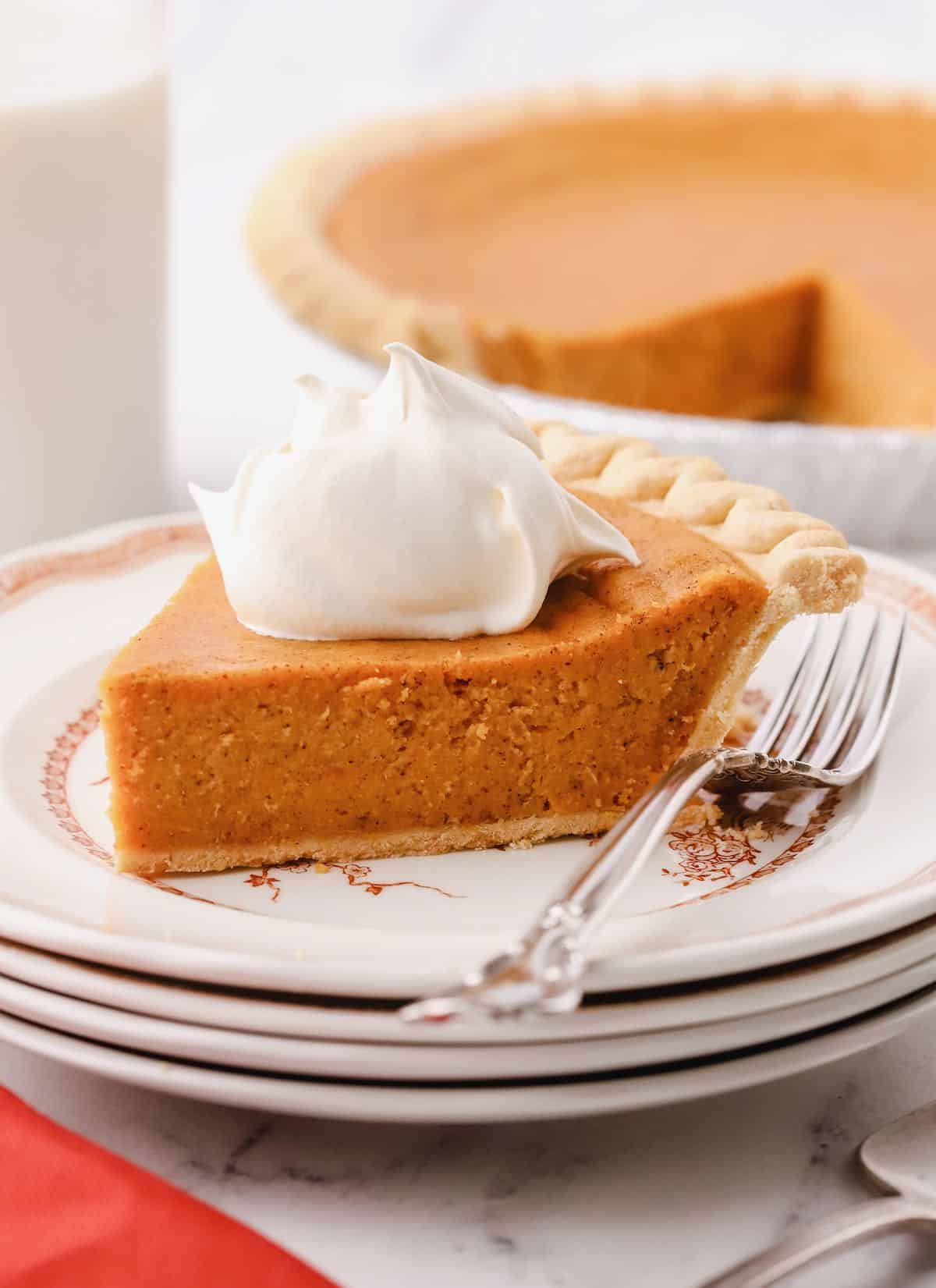 A slice of southern sweet potato pie on a plate topped with whipped cream.