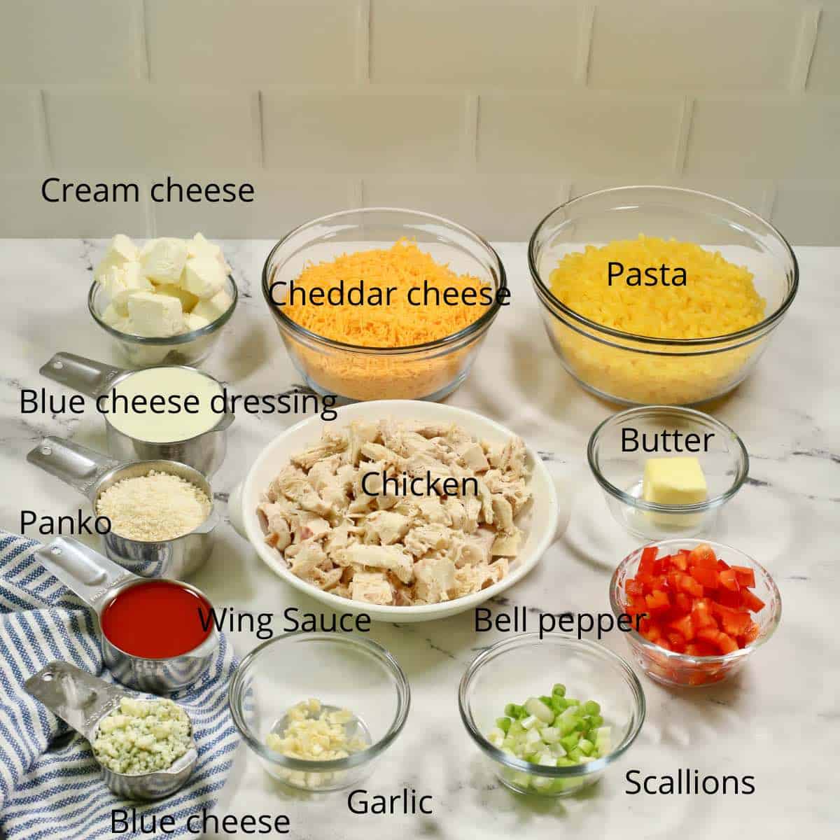 A large bowl of shredded chicken, pasta, cheese and other ingredients to make a chicken and pasta casserole. 