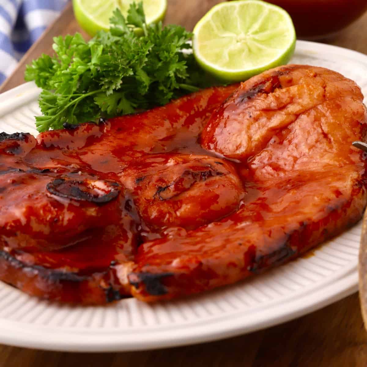 A grilled ham steak topped with apricot glaze on a white plate.