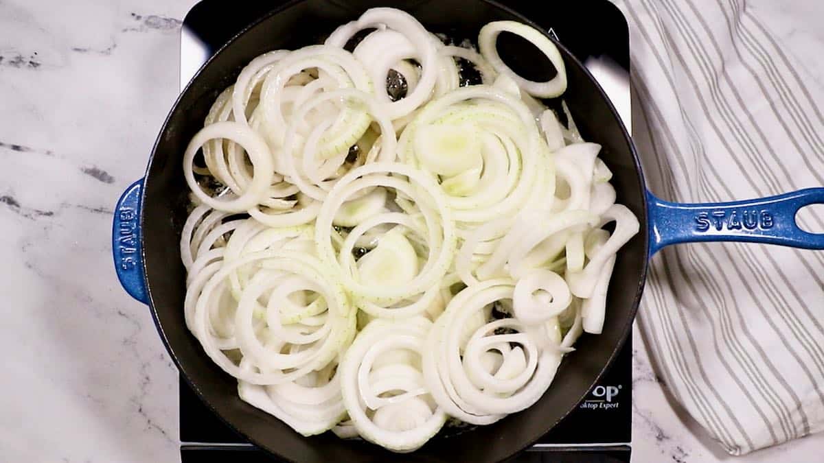 Sliced onions cooking in a cast iron skillet. 