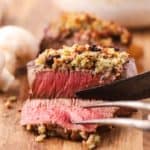 A filet mignon topped with blue cheese on a cutting board.