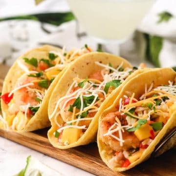 Fried shrimp tacos on a cutting board.