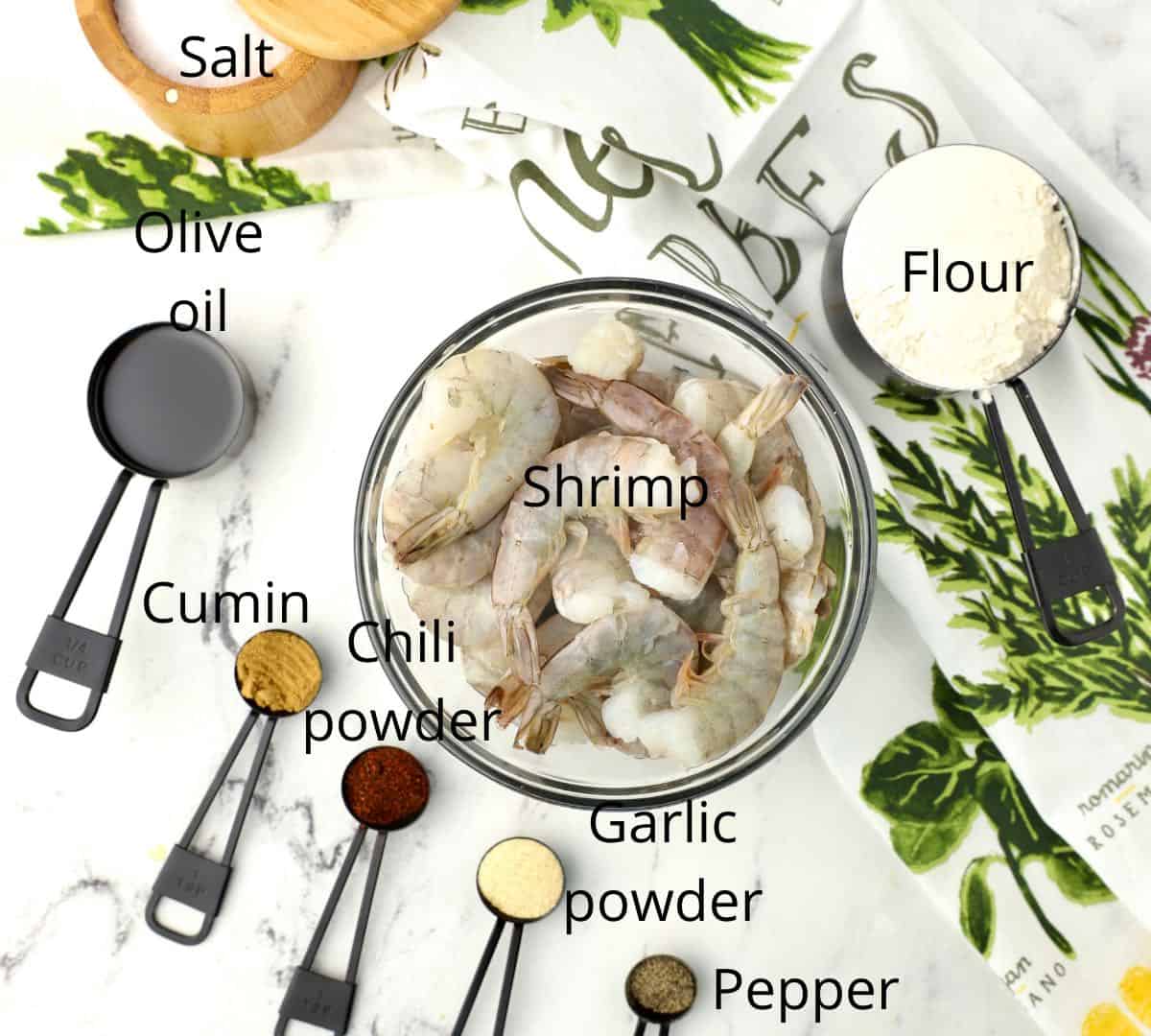 A bowl of fresh shrimp, seasonings and flour. 