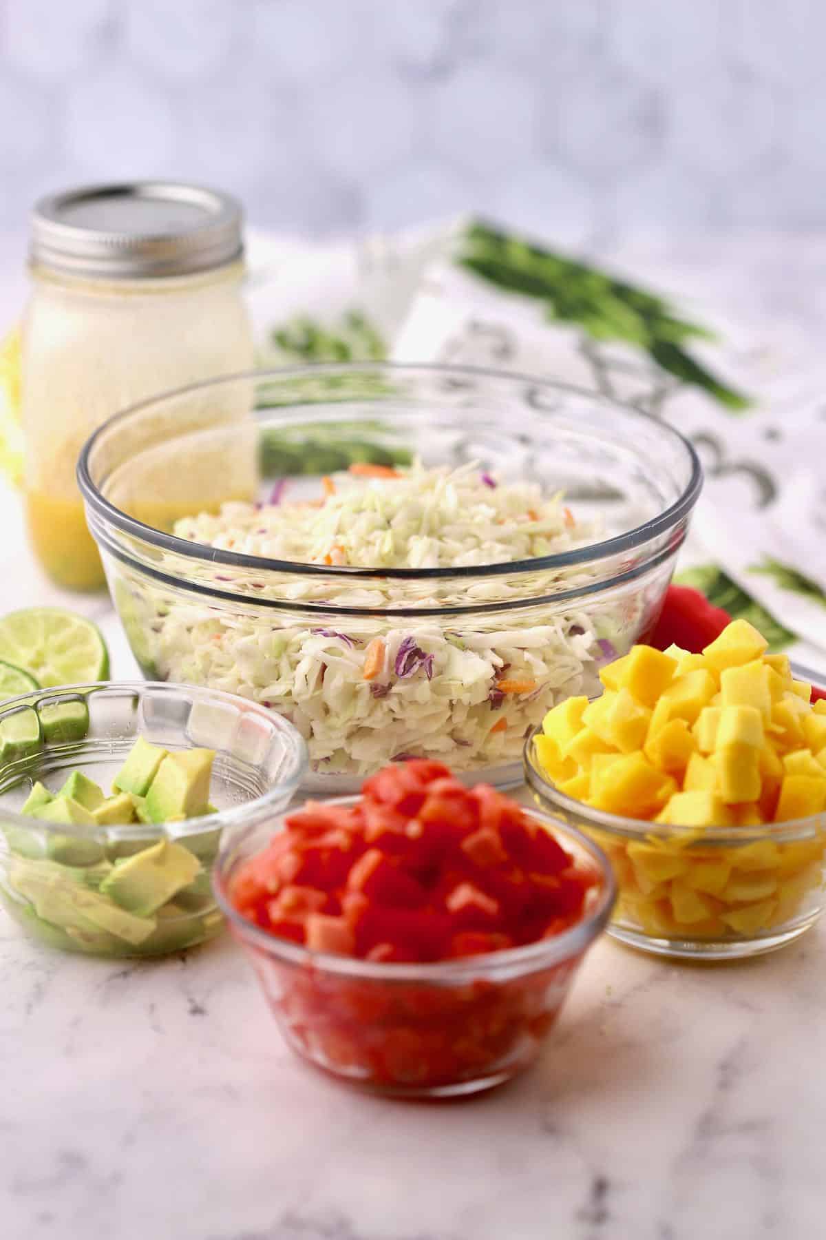 Coleslaw in a bowl with chopped mango and tomatoes. 