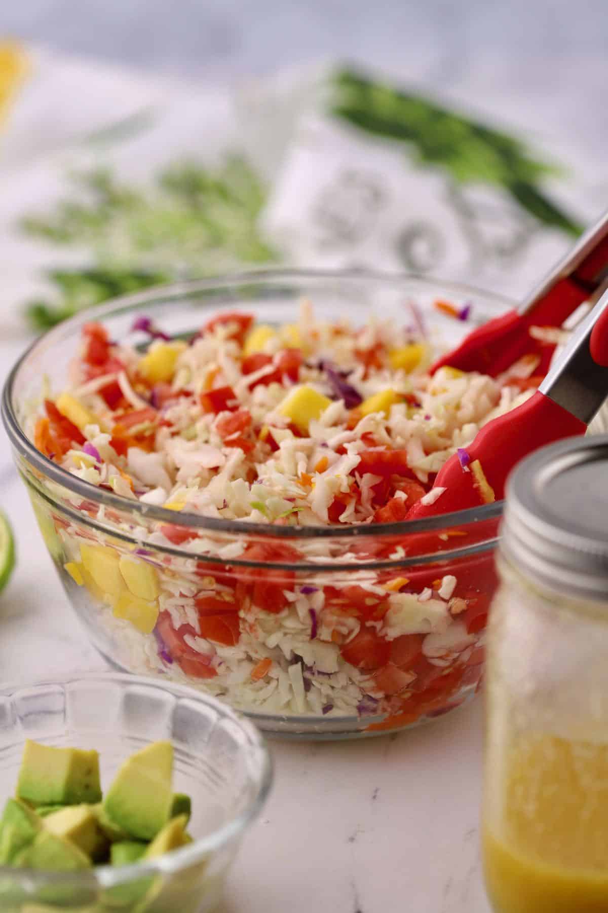 Mango slaw in a clear glass bowl. 