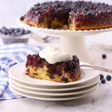 A slice of blueberry upside-down cake topped with a dollop of whipped cream.