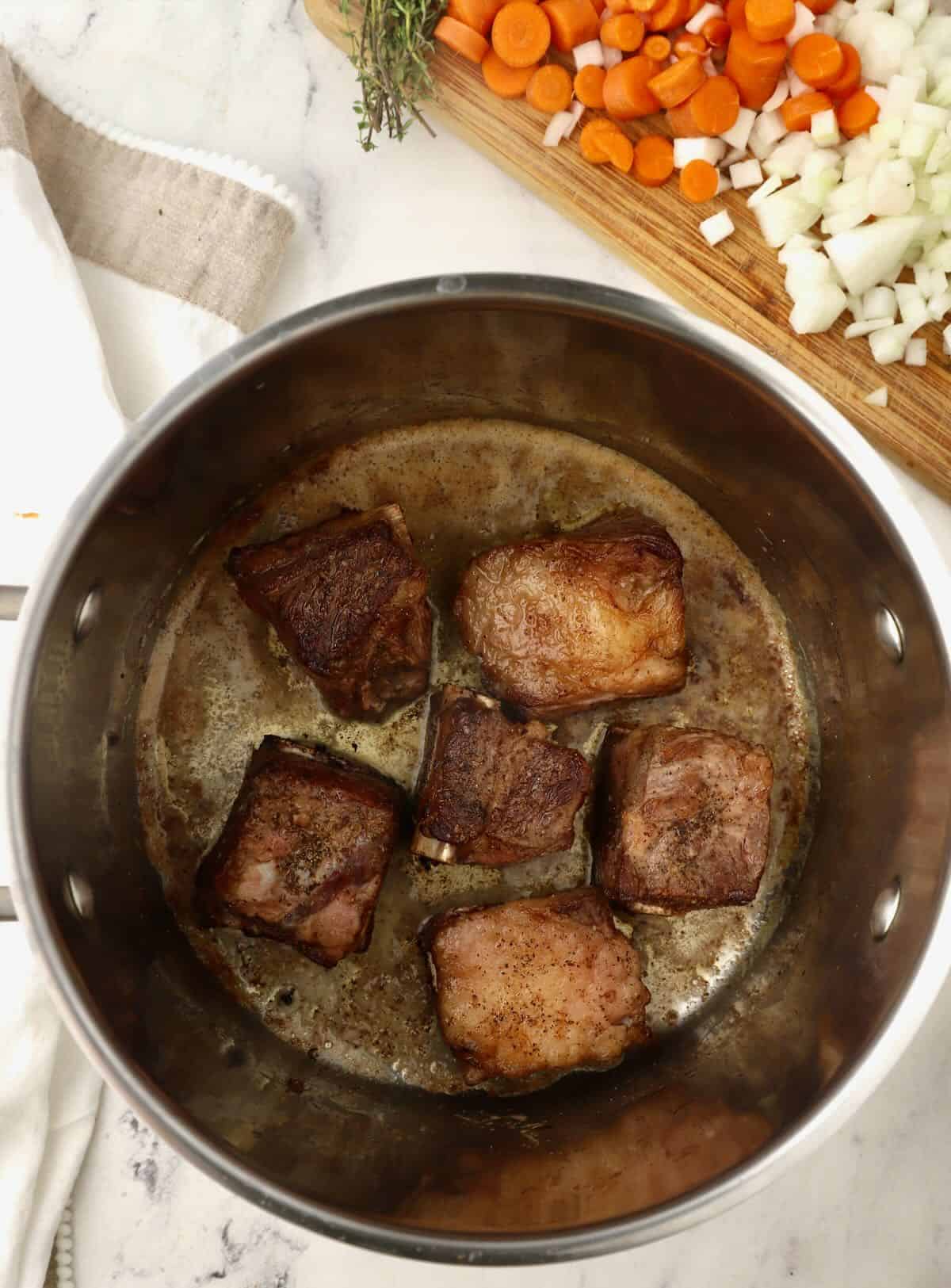 Searing beef short ribs in a stock pot. 