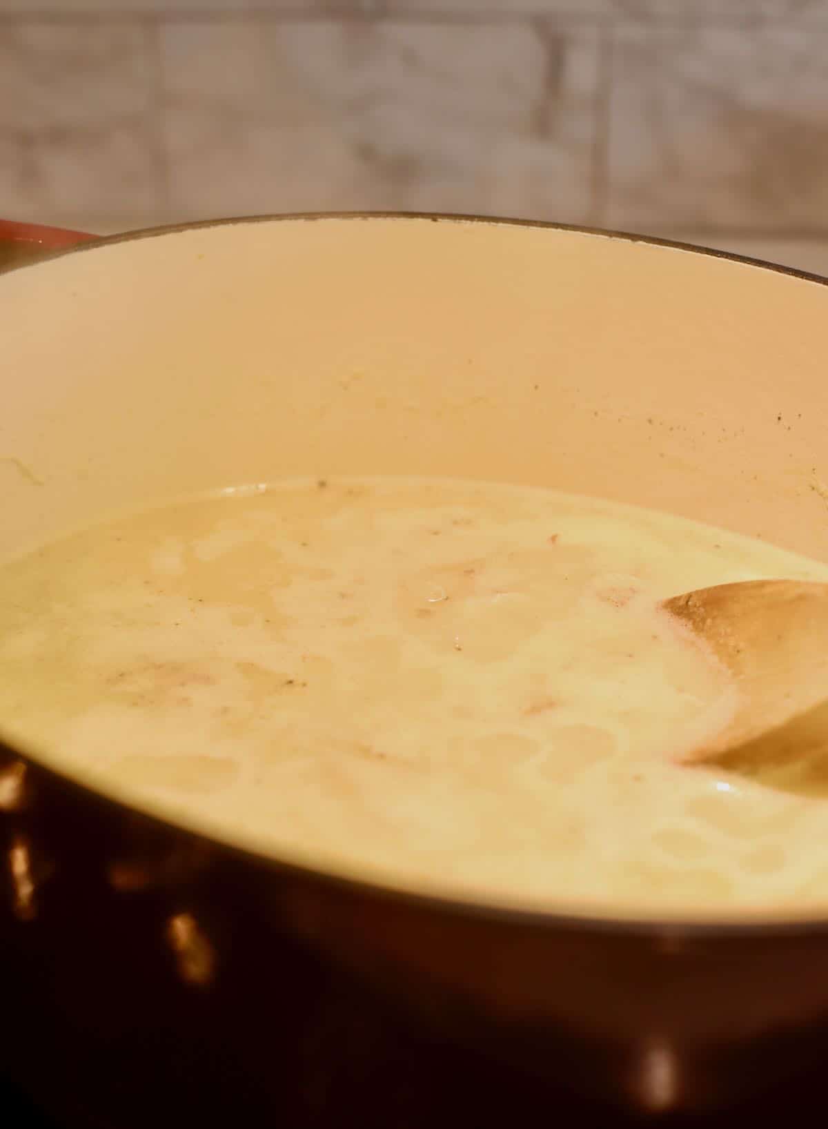 A dutch oven full of chicken and dumplings stock. 