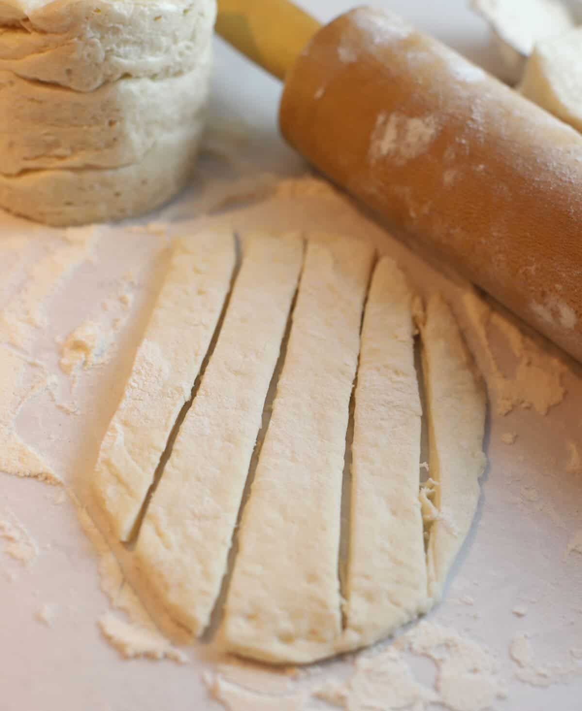 A refrigerated raw biscuit rolled out and cut into strips. 