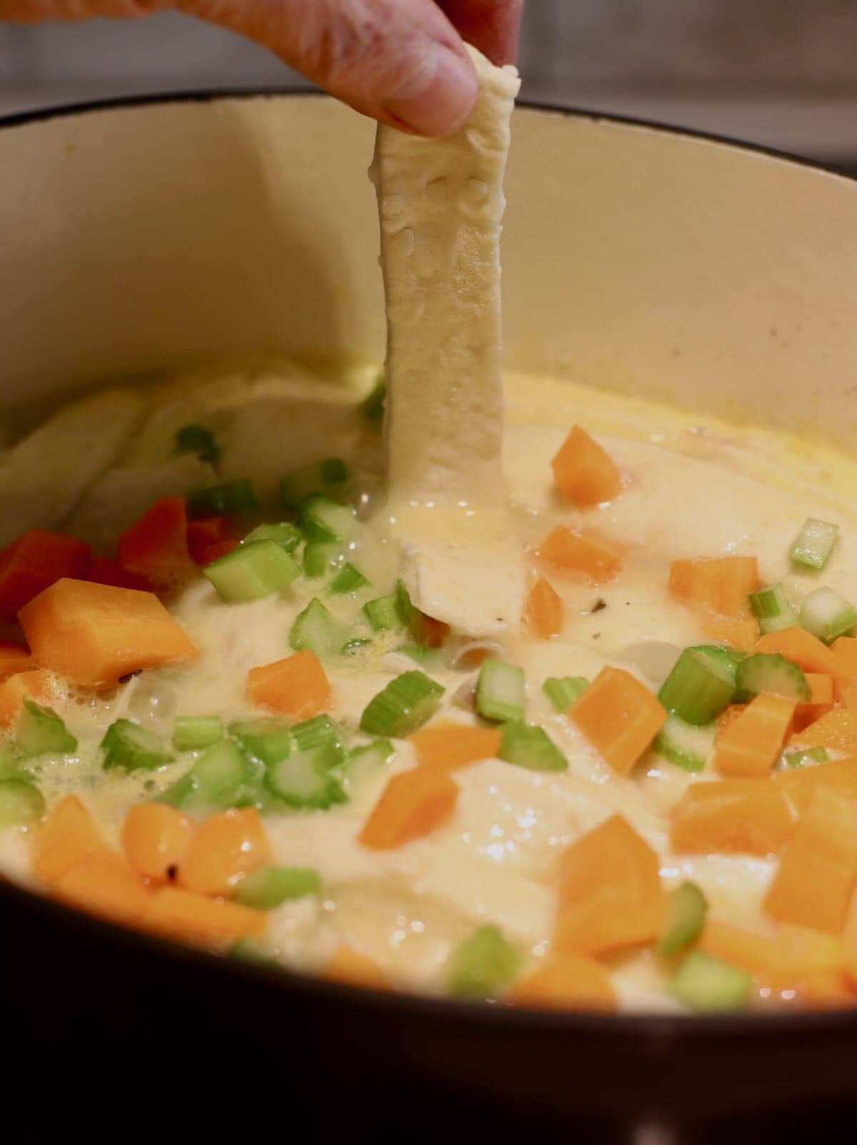 Dropping a dumpling into a large dutch oven full of chicken and dumplings. 