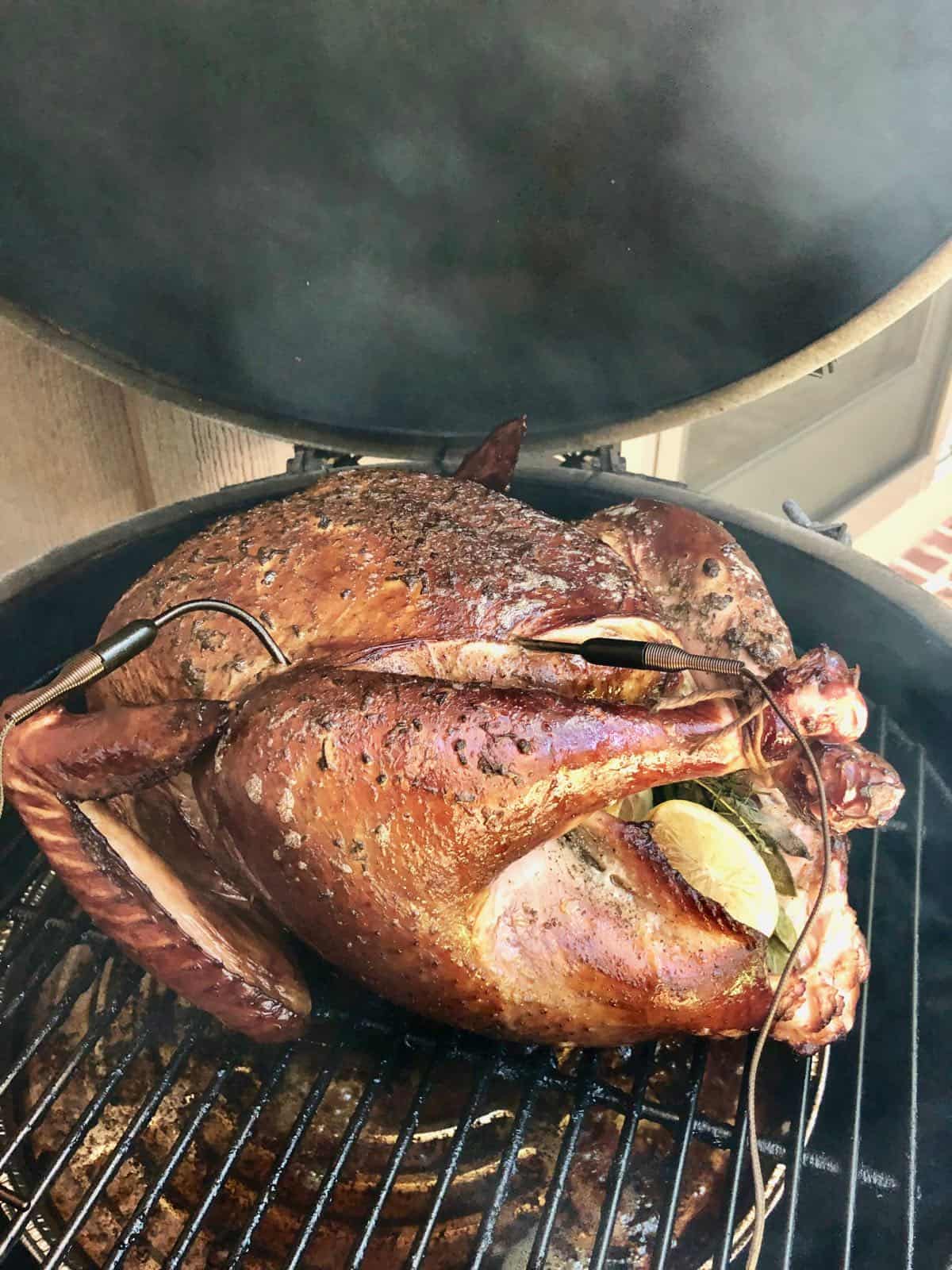A smoked turkey cooking on a grill. 