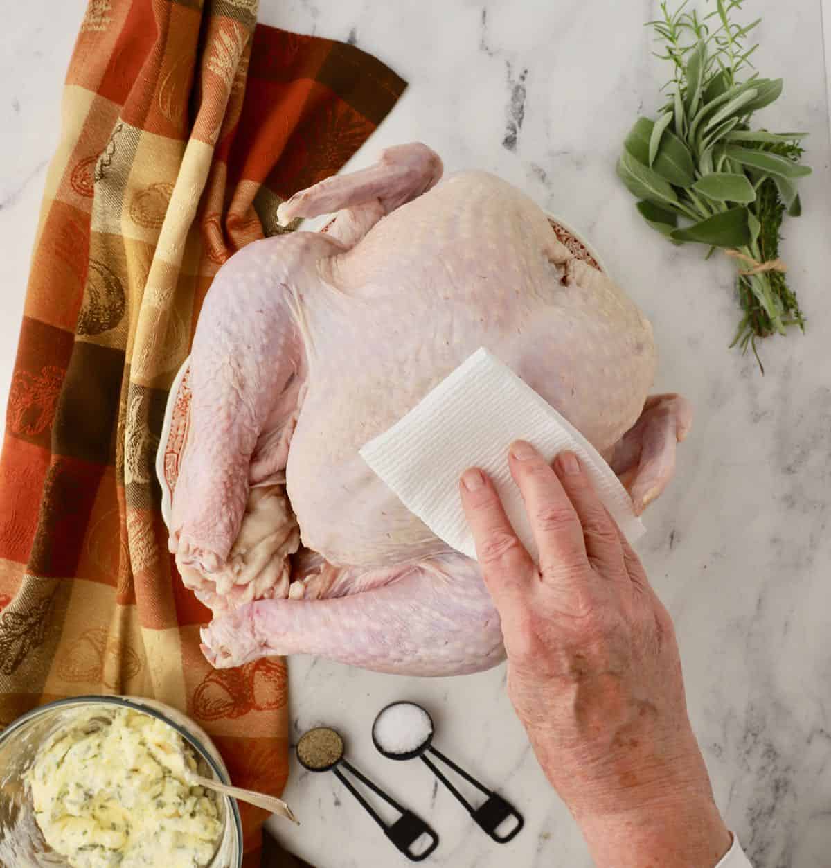 Using a paper towel to dry off a turkey. 