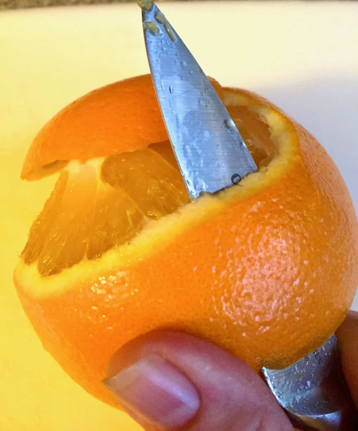 Using a paring knife to peel an orange. 