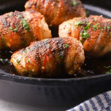 Bacon wrapped chicken thighs in a cast iron skillet.