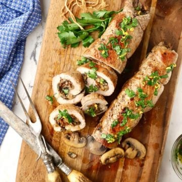 Mushroom stuffed pork tenderloin on a wooden cutting board.