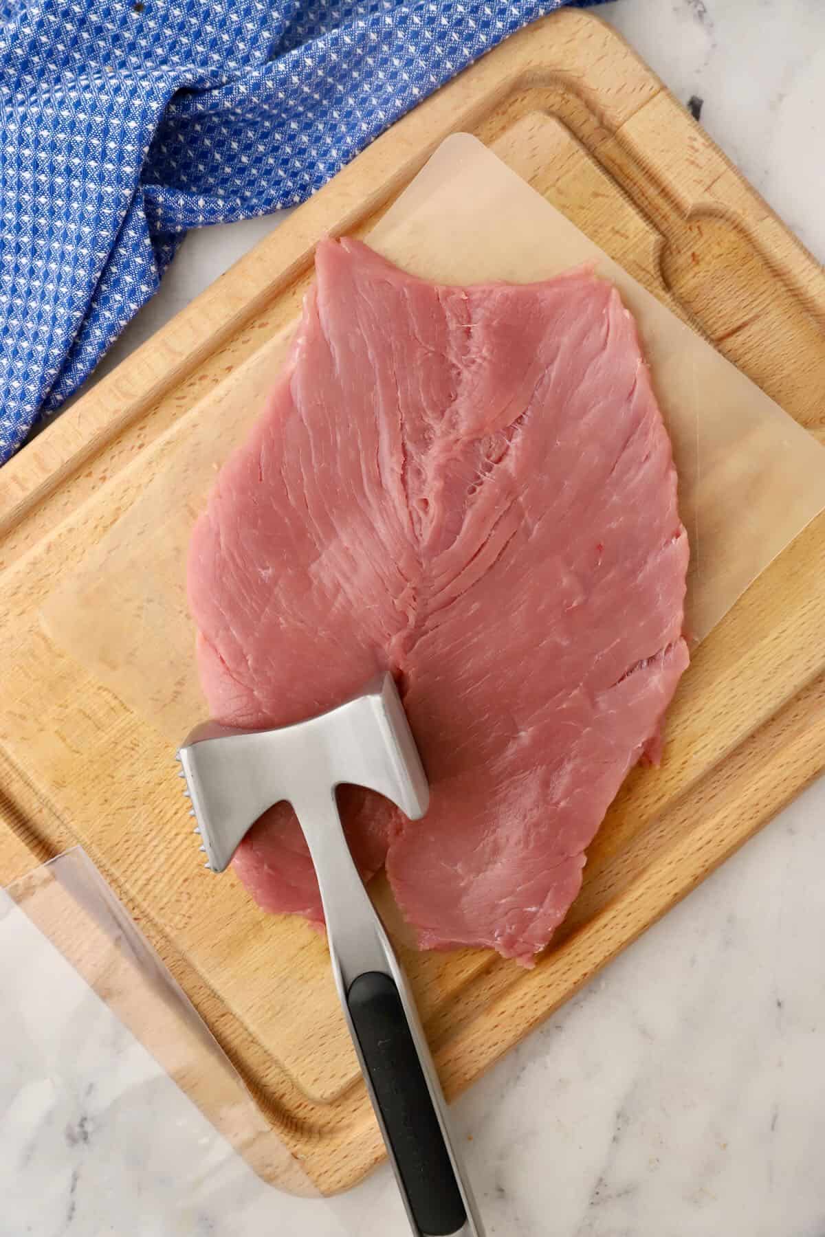 A butterflied pork tenderloin on a cutting board. 