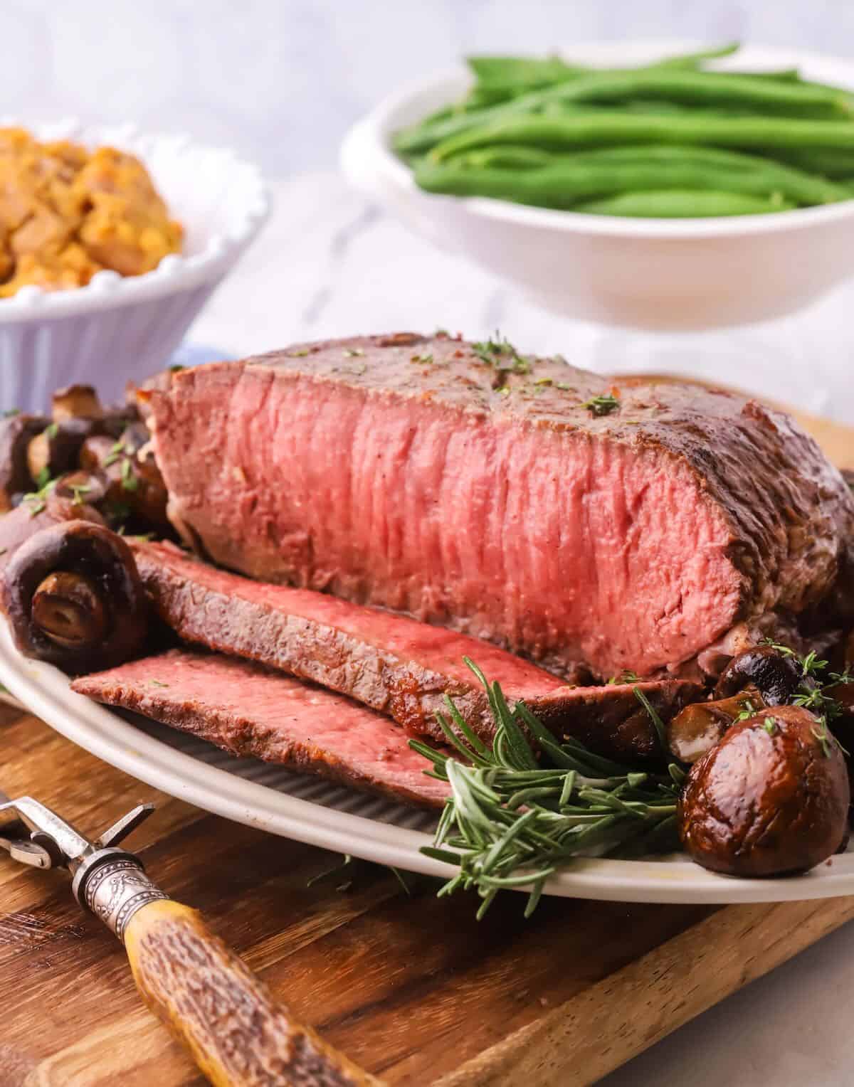 A New York Strip Roast sliced with mushrooms.