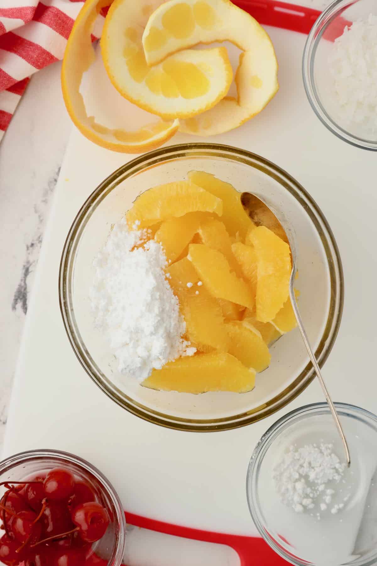 A bowl of orange segments topped with powdered sugar. 