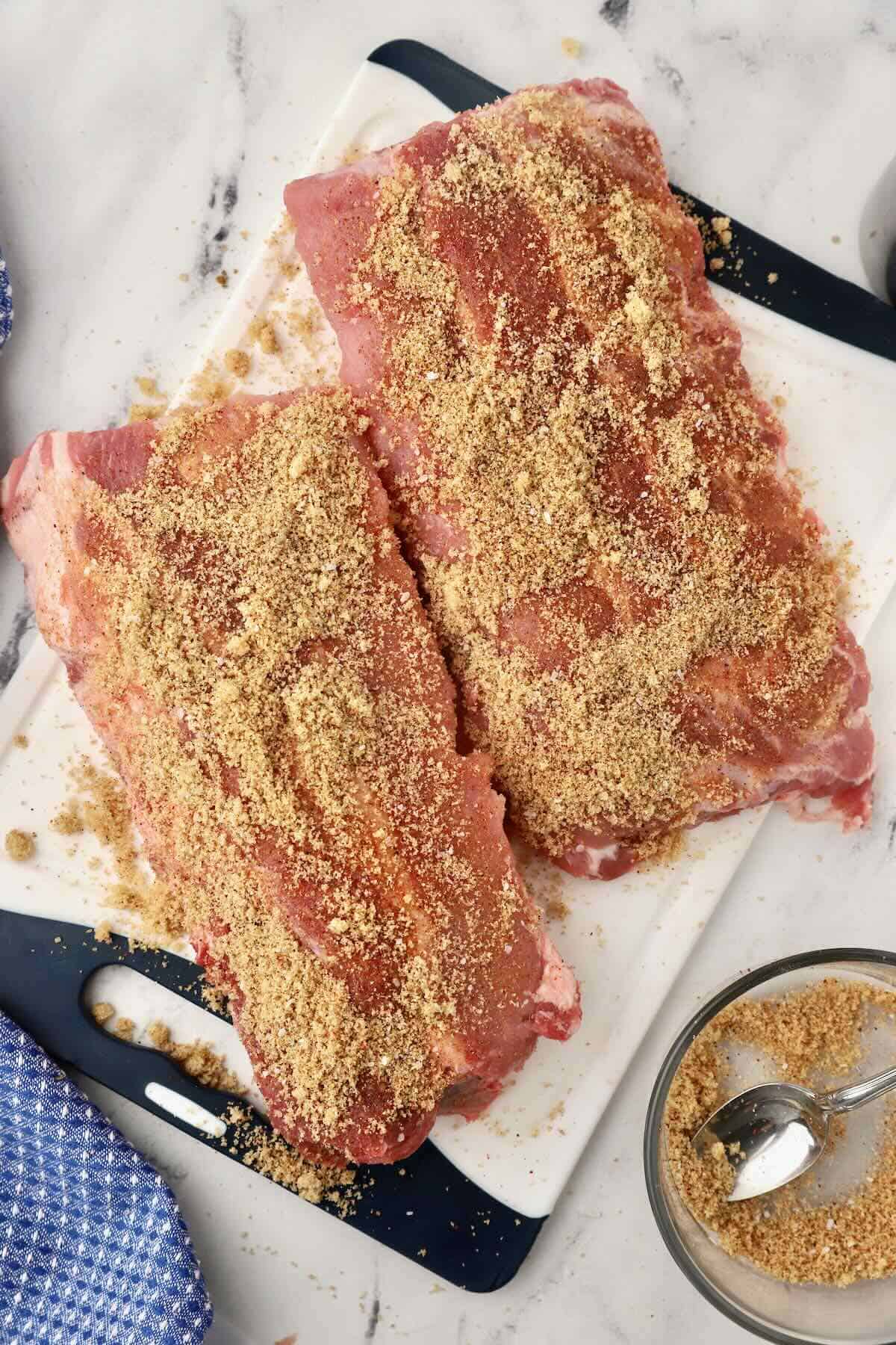 Two racks of pork ribs topped with dry rub. 