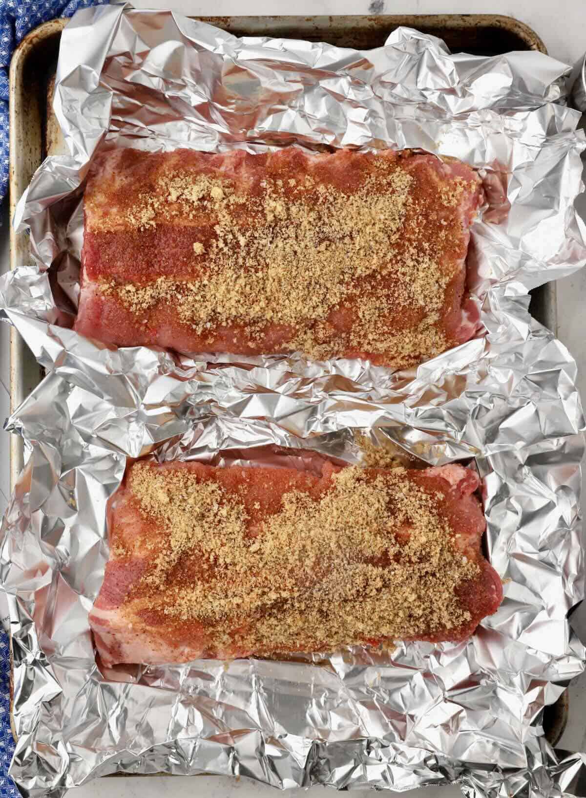 Two racks of baby back ribs on a baking sheet.