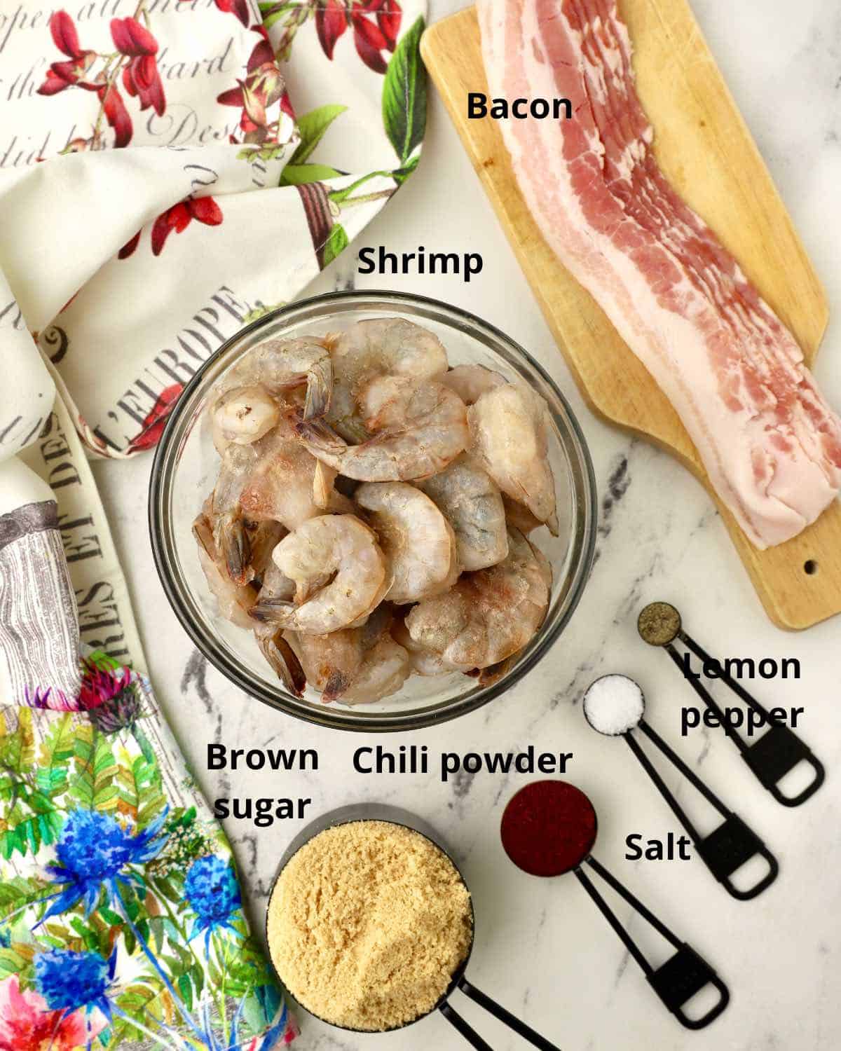 A bowl of raw shrimp, bacon and seasonings for bacon wrapped shrimp. 