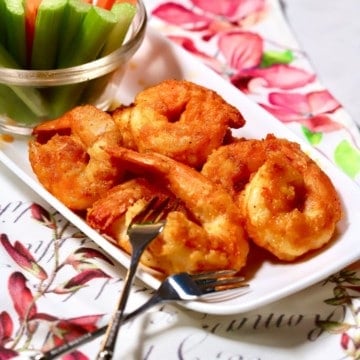 Buffalo shrimp on a plate with cocktail forks.