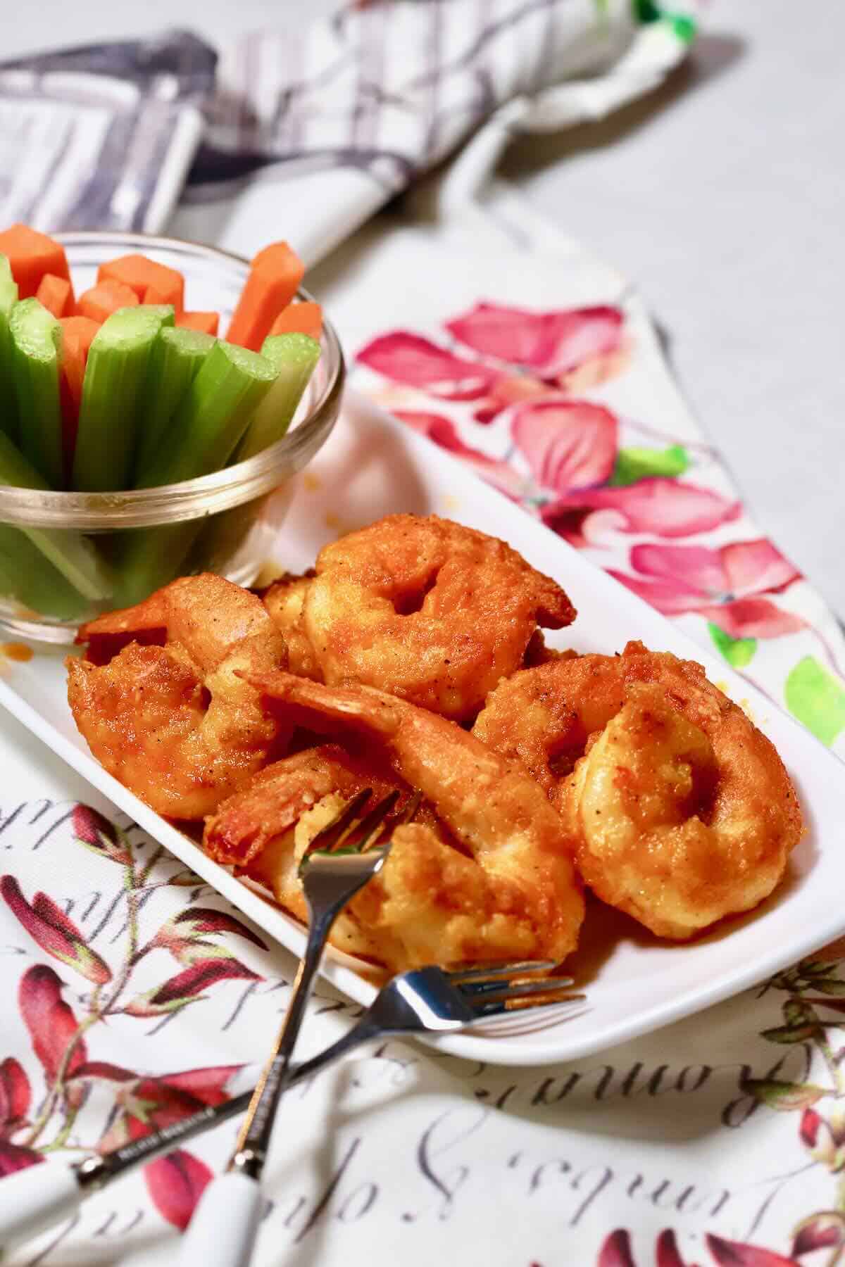 Buffalo shrimp on a plate with carrots and celery. 