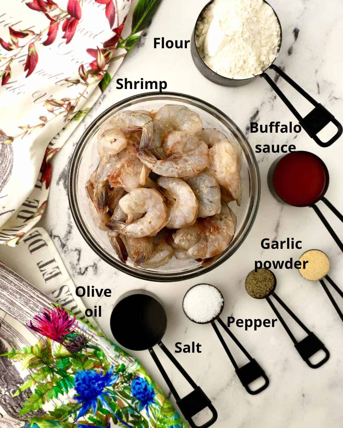 A bowl of raw shrimp and other ingredients for buffalo shrimp.