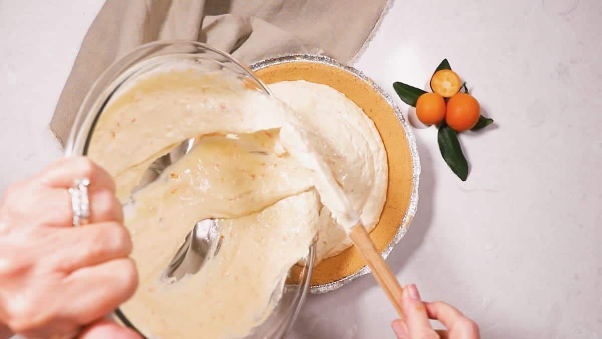 Pouring kumquat pie filling into a graham cracker crust. 