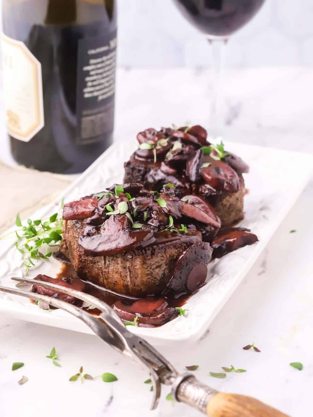 Two filet mignons topped with red wine mushroom sauce. 