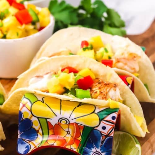 Two fish tacos topped with mango salsa.