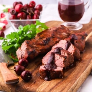 Sliced grilled pork tenderloin on a cutting board.