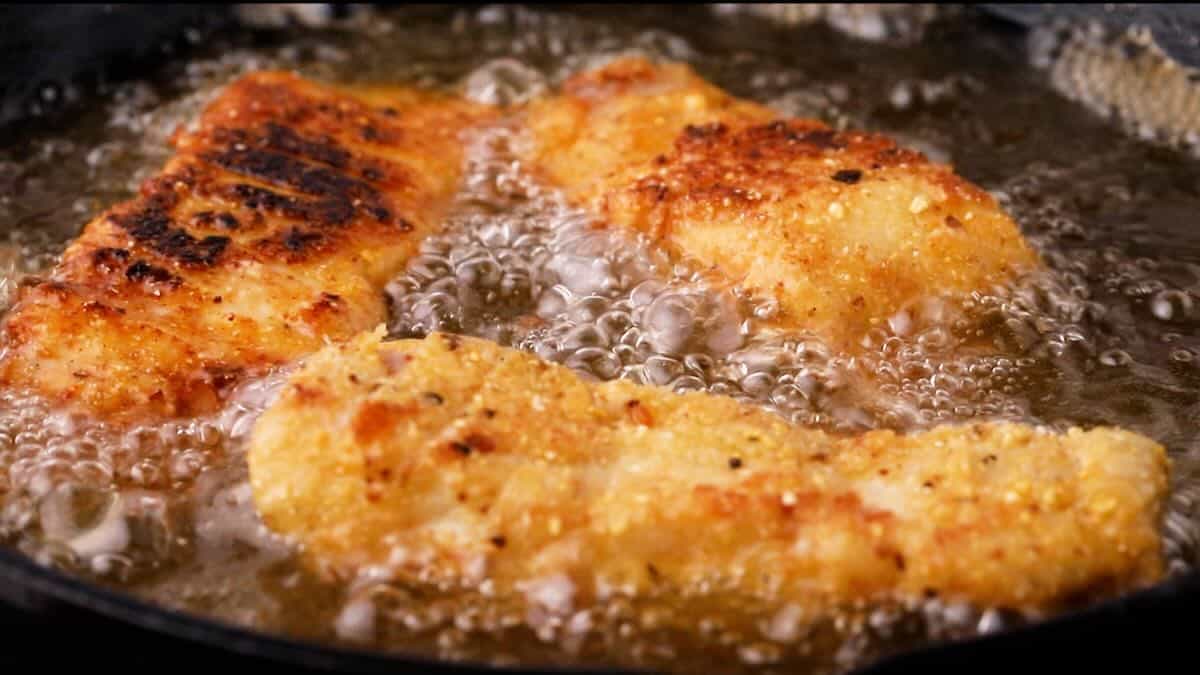 Grouper fillets frying in a cast-iron skillet. 