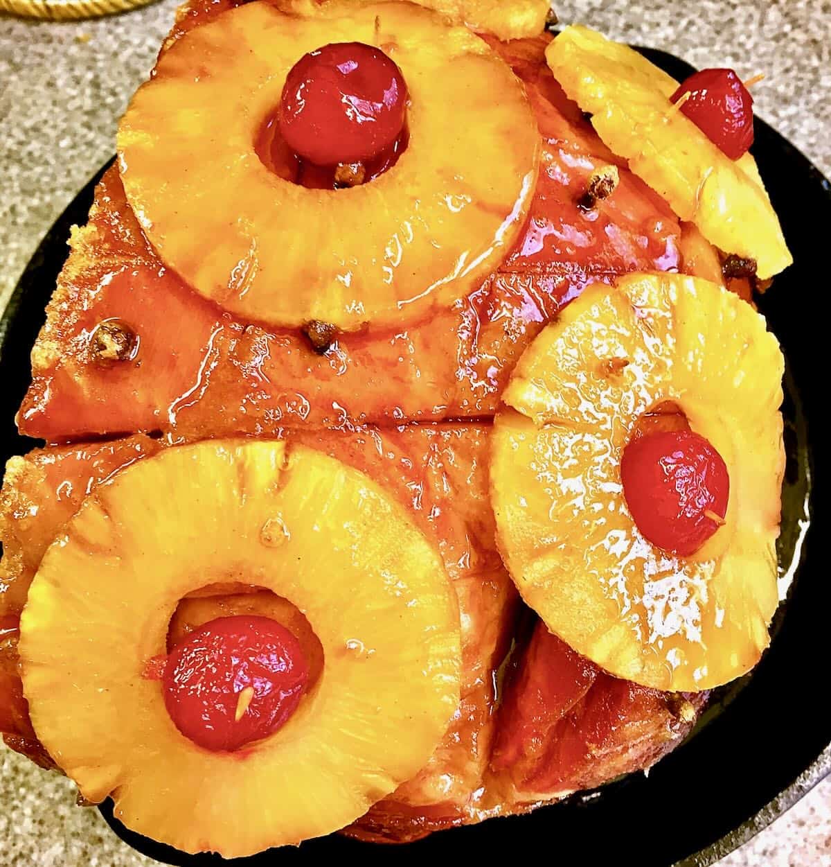 A ham topped with pineapple rings and cherries. 