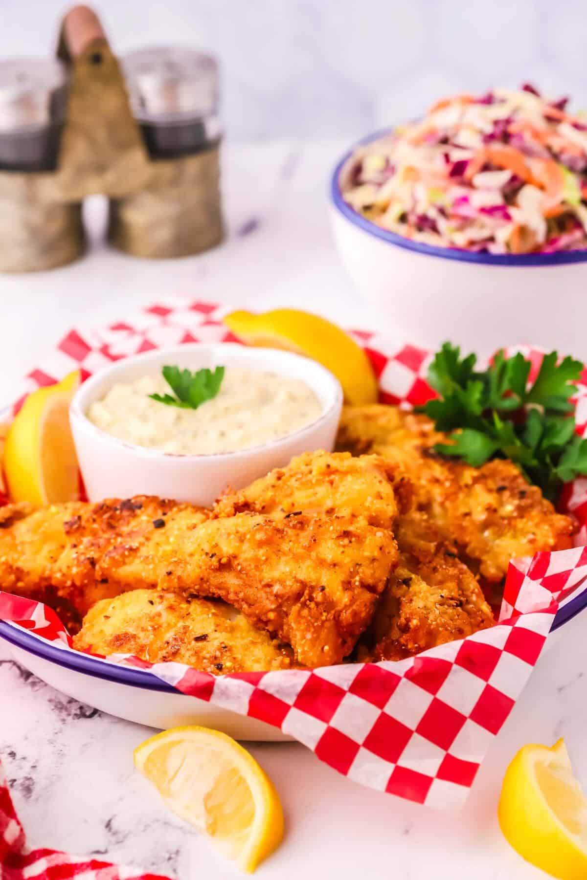 Fried grouper in a serving dish with a bowl of tartar sauce. 