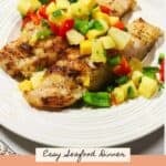 Grilled grouper fillets on a plate topped with fresh mango salsa.