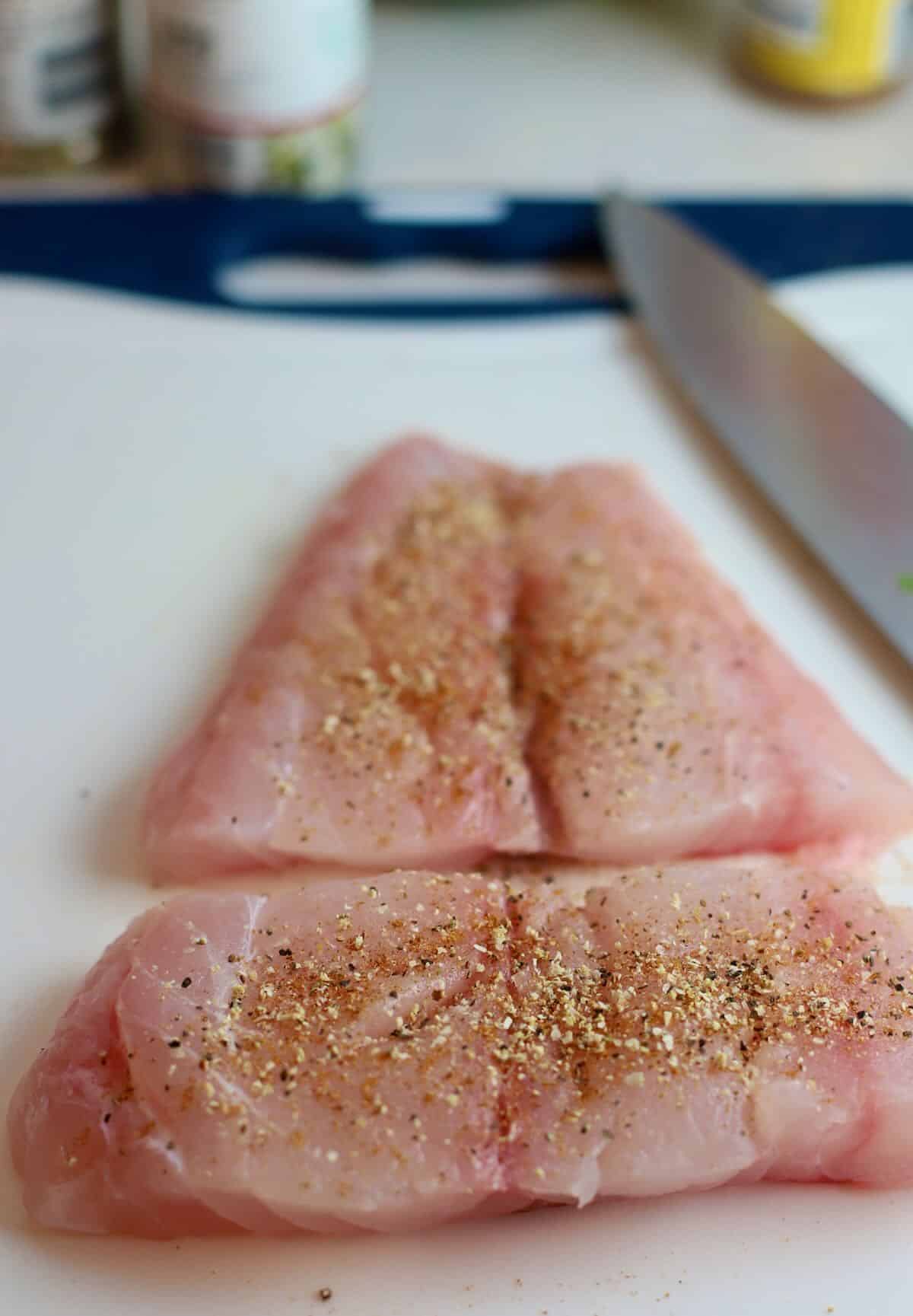 A snapper fillet cut in half and seasoned with salt and pepper. 