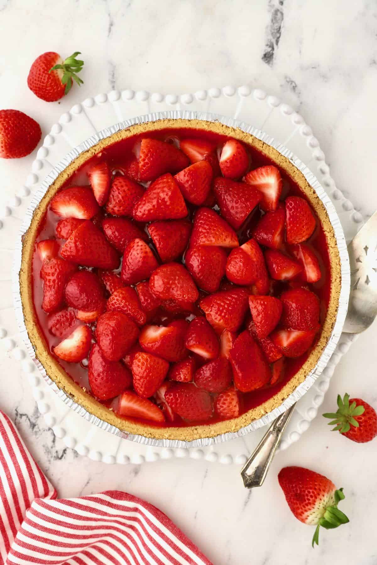 A whole strawberry pie on a white plate.