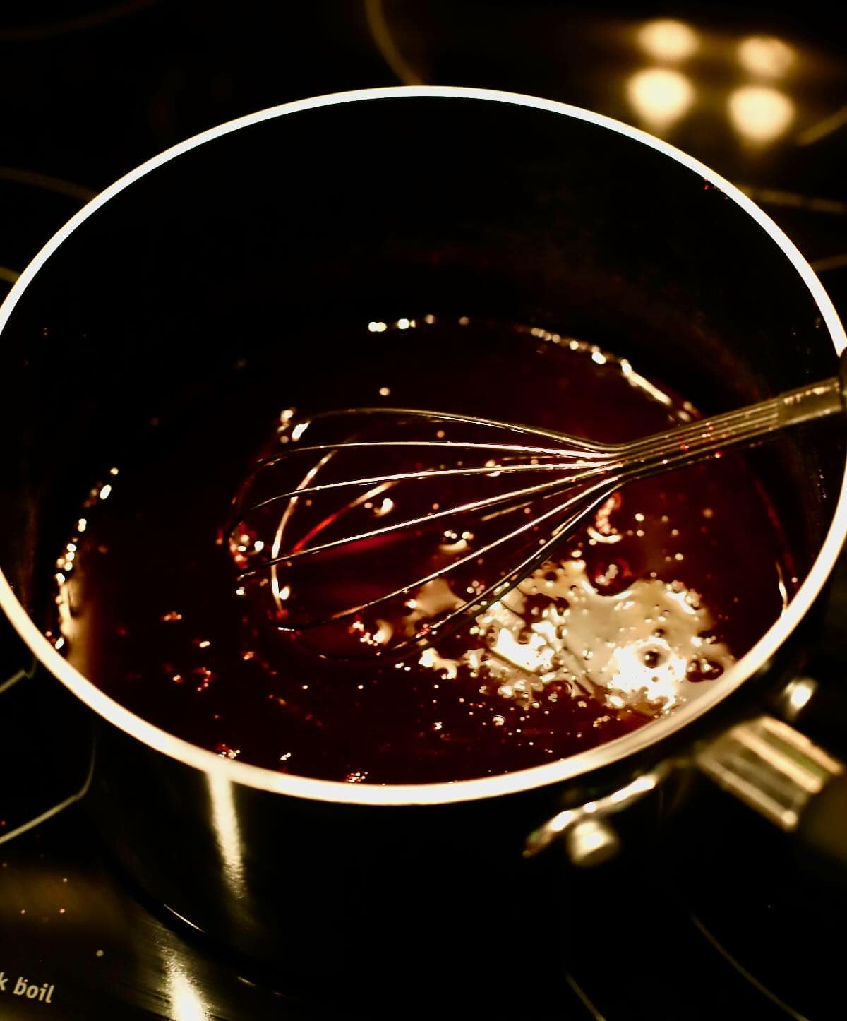 Strawberry glaze cooking in a saucepan. 